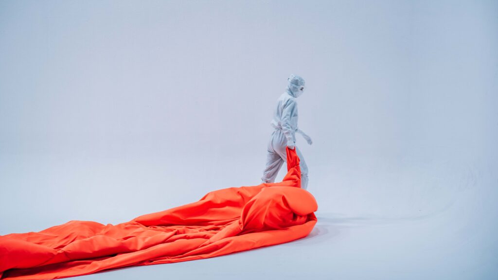 Model in cleanroomkleding met oranje stof op witte studieset voor Dastex productvideo