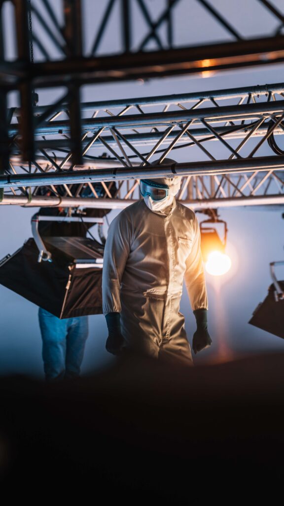 Model in cleanroomkleding poseert onder studiolampen op de Dastex filmset
