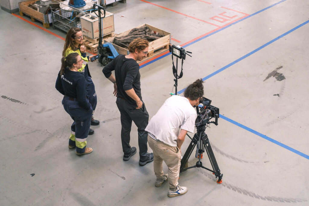 Regisseur en cameraploeg bereiden scène voor in industriële omgeving, Equans