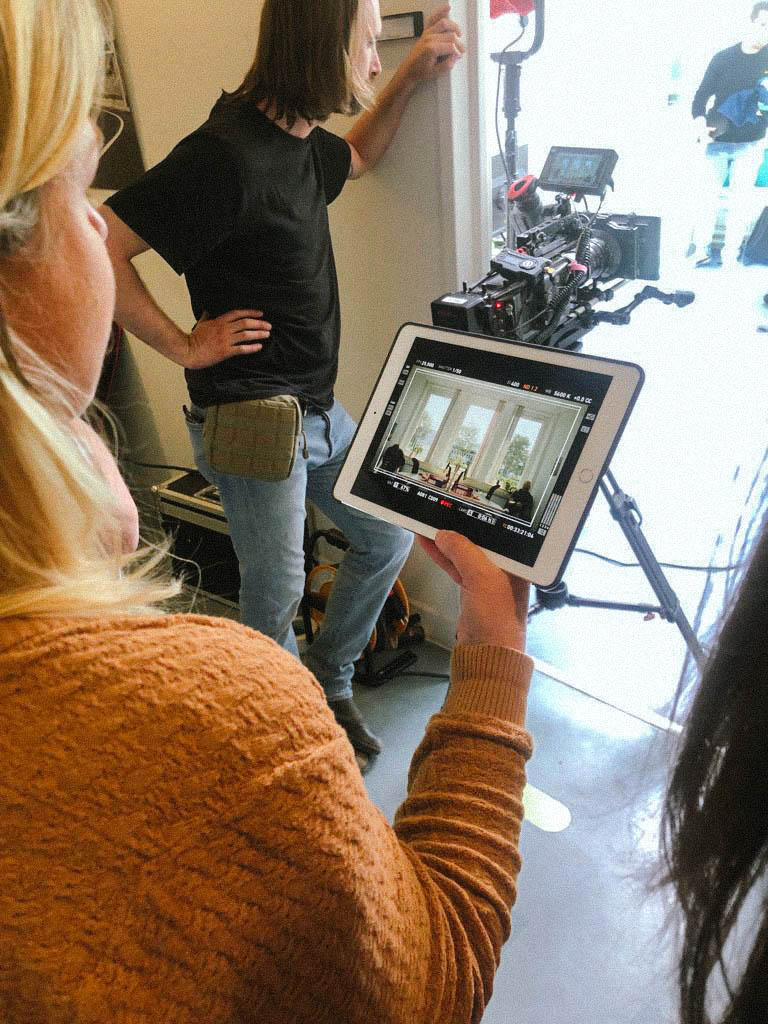 Assistent bekijkt monitor tijdens opnames, behind the scenes Equans employer branding