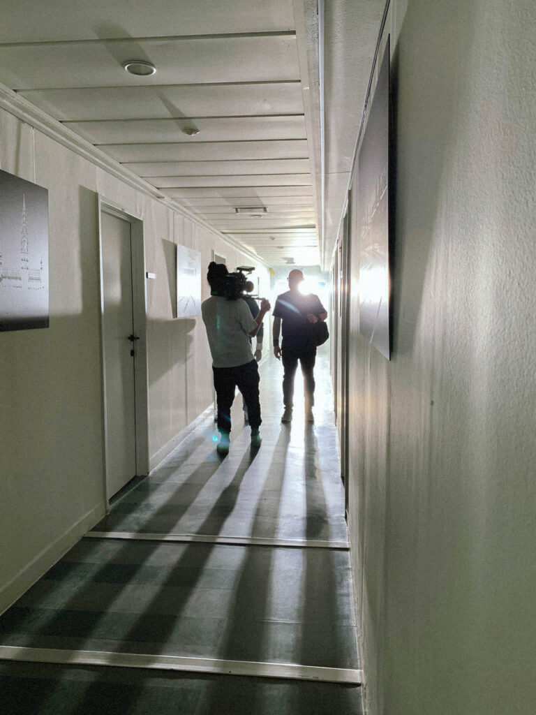 Twee medewerkers lopen door verlichte industriële gang tijdens opnames Equans