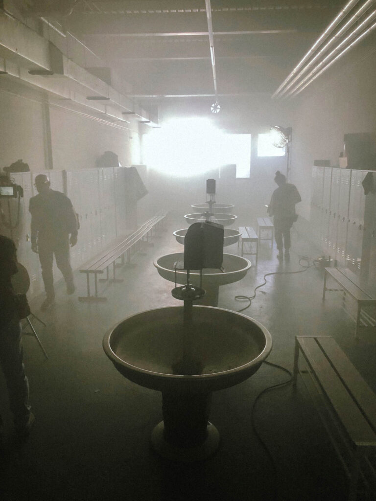 Grote verlichte filmset met statief in industriële omgeving, Equans productie