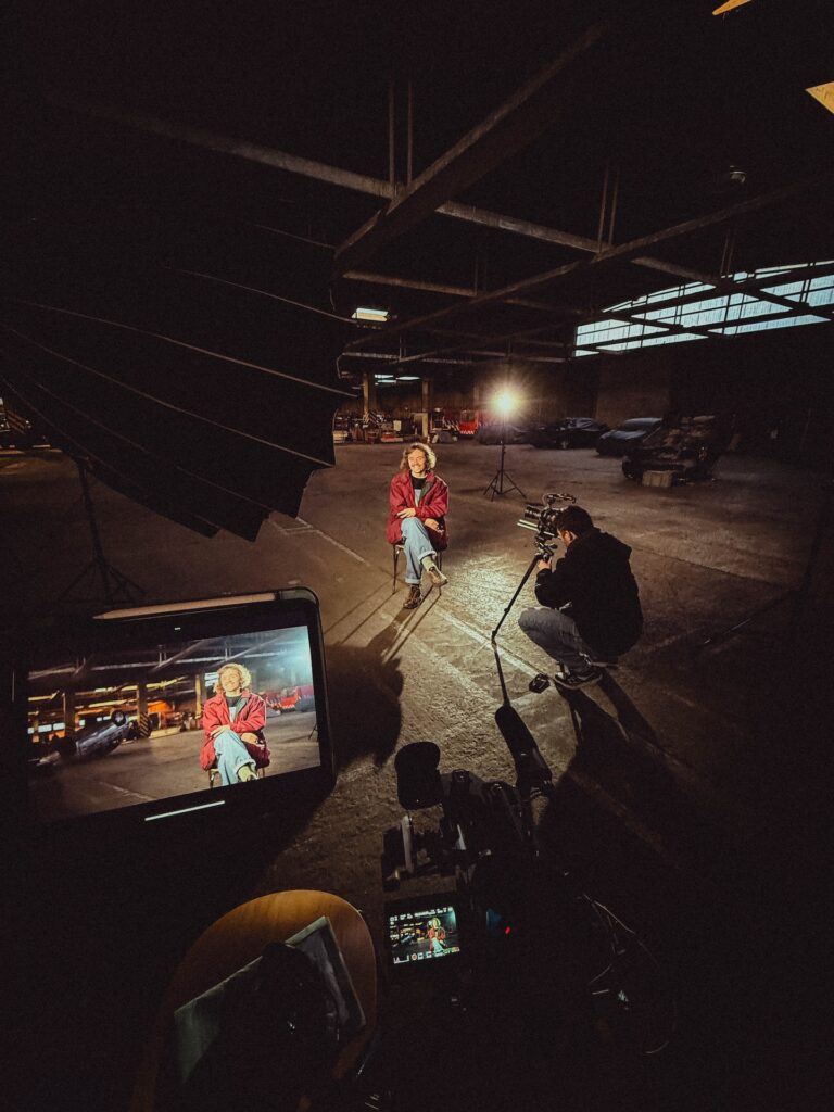 Filmset met camera en verlichting in donkere industriële hal, behind the scenes Europese Commissie