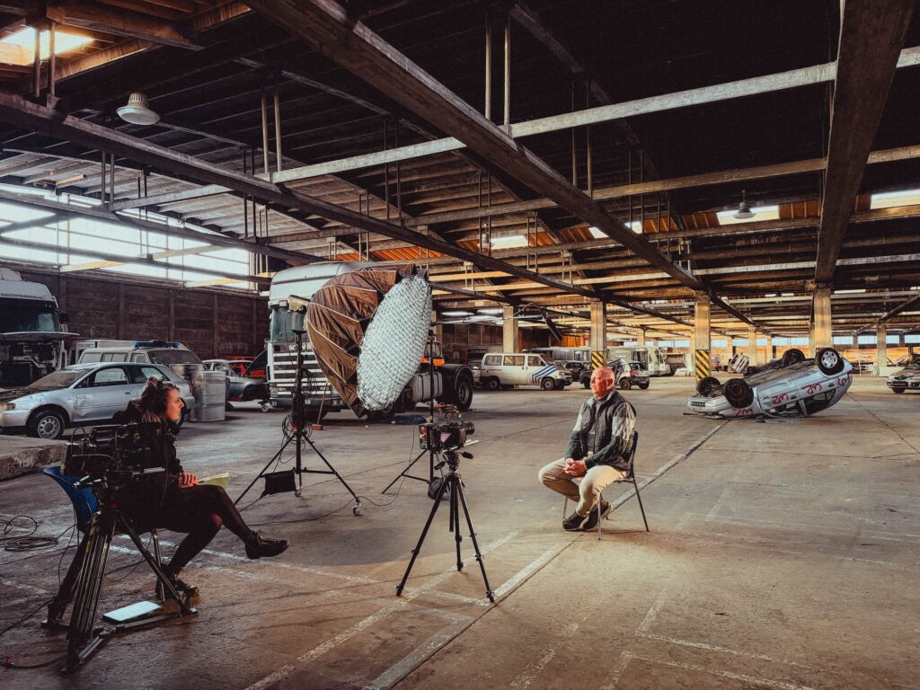 Grote verlichte filmset in industriële ruimte met groot scherm op achtergrond