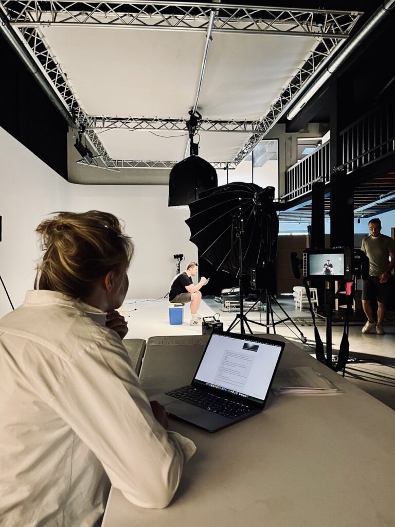 Crewlid bekijkt opnames op laptop tijdens pauze op set, behind the scenes Weber commercial