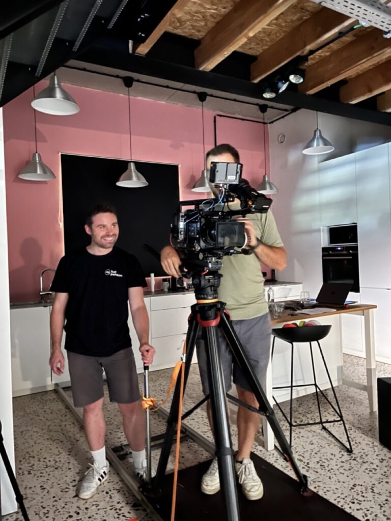Cameraman met statief in roze verlichte studio, behind the scenes Weber commercial