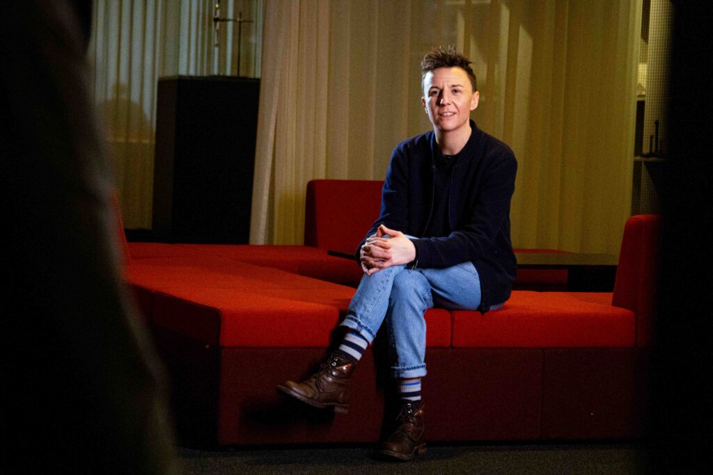 Acteur zit ontspannen op rode bank tijdens interview voor GUM video, behind the scenes