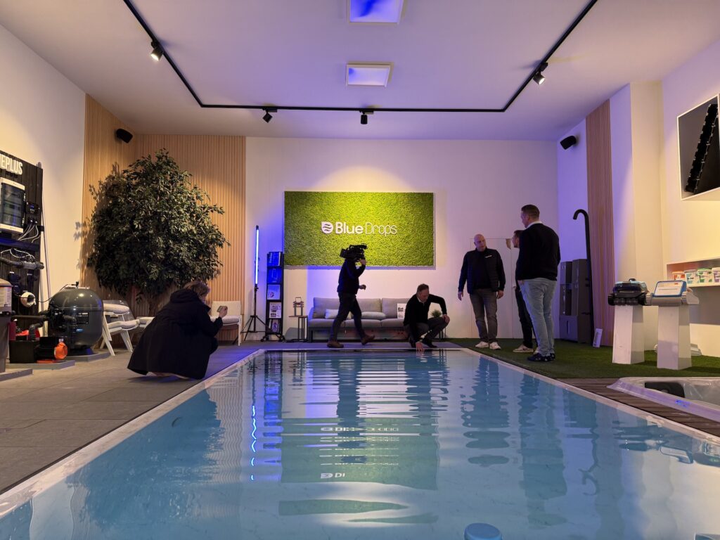 Crew bereidt scène voor in verlichte Bluedrops showroom met binnenzwembad