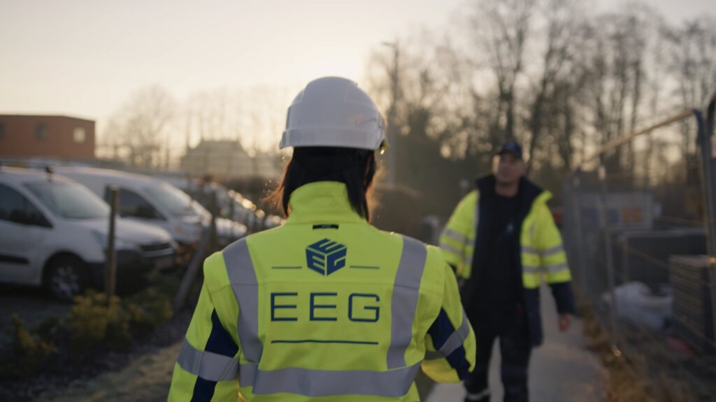 EEG medewerker met helm van achteren gezien op een bouwwerf