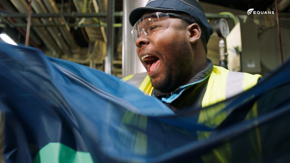 Equans medewerker met blauwe cape kijkt enthousiast, still uit employer branding reeks